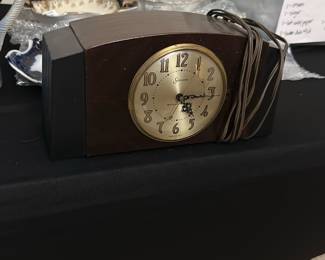 Sessions Electric Mantel Clock — This vintage Sessions electric mantel clock features a classic curved dark wood case with a brass bezel surrounding the silvered dial. The clock face presents bold black Arabic numerals and ornate hands, combining both elegance and readability. Measuring approximately 6.5 inches tall, 11 inches wide, and 4 inches deep, it is a perfect addition to a bedroom or living room mantle. The clock is in good condition with minor surface wear consistent with its age and includes the original power cord. A fine example of mid-20th century American clockmaking from the well-known Sessions brand.