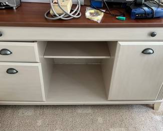 Light Wood Office Desk Cabinet — This light wood office desk cabinet offers practical storage and workspace with a natural wood top and a painted base. Featuring two drawers, a cabinet door, and a keyboard tray, it provides versatile storage options for any office or workroom. Estimated measurements are approximately 30 inches high, 48 inches wide, and 20 inches deep, making it a medium-sized desk solution. The condition is good with minor signs of use consistent with normal office wear. This piece is well-suited for an office up room setting, blending functionality with a neutral color palette.