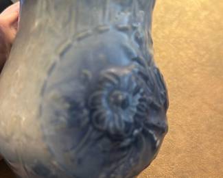 Blue Floral Ceramic Vase — This charming blue ceramic vase features an embossed floral pattern with intricate details. Its unique flared and scalloped rim adds character to this decorative piece, ideal for dining room display or flower arrangements. The vase measures approximately 5 in height and 3.5 in width, making it a perfect accent for small spaces. It is in good condition with minor surface wear consistent with age but no visible chips or cracks. A lovely example of vintage home decor suitable for collectors or daily use.