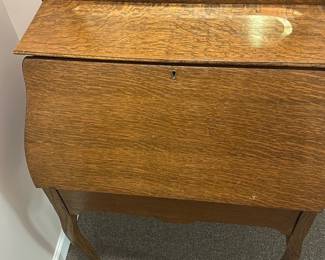 Vintage Oak Writing Desk with Mirror — This vintage oak writing desk features a built-in mirror with a rounded rectangular frame, adding both functionality and charm. The drop-front desk opens to reveal multiple internal compartments and a small drawer, perfect for organizing stationery and writing tools. Measuring approximately 40 inches high, 30 inches wide, and 18 inches deep, it stands on elegantly curved legs that enhance its classic appeal. The desk is in good condition with minor surface wear consistent with age, and the mirror remains intact without cracks. Ideal for a basement room or cozy study, this piece showcases solid oak craftsmanship and a timeless design.