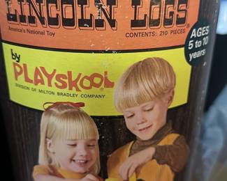 Original Lincoln Logs Playskool Set — This vintage Original Lincoln Logs set by Playskool, a division of Milton Bradley Company, offers 210 pieces for creative building play. Designed for ages 5 to 10 years, the set comes in a cylindrical container showcasing classic wood-like design and images of children playing with Lincoln Logs. The toy set promotes imaginative construction and fine motor skills development. The container shows signs of wear and tear typical of vintage items. A nostalgic, educational toy perfect for collectors or kids interested in traditional building sets.