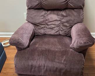 La-Z-Boy Purple Recliner Chair — This La-Z-Boy recliner chair features a plush purple upholstery perfect for cozy basement living spaces. Constructed with soft, textured fabric and padded armrests, it offers excellent comfort and support. The recliner measures approximately 40 inches in height, 36 inches in width, and 38 inches in depth, making it a generously sized seating option. The chair is in good condition with minor signs of use but remains fully functional. La-Z-Boy's quality craftsmanship ensures durability and long-lasting comfort.