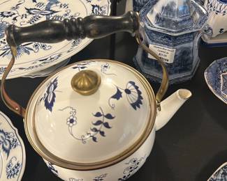 Blue Danube White and Blue Teapot — This charming Blue Danube teapot features classic white porcelain adorned with delicate blue floral patterns and a brass-colored lid handle. It includes a black wooden handle with brass accents, blending function with traditional style. The teapot measures approximately 5.5 inches in height, 6.5 inches in width, and 9 inches in length, making it a practical yet elegant addition to any tea set or display. The teapot is in good condition with minor wear visible on the base typical of vintage porcelain items. Marked clearly on the bottom with the Blue Danube logo, this piece represents classic mid-20th century design.