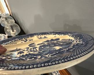 Blue Willow Japan Divided Plate — This Blue Willow divided plate features classic blue and white scenic design, crafted in Japan. The plate is made of ceramic with three compartments, ideal for serving multiple dishes or appetizers. Measuring approximately 10 inches in diameter, it offers practical use with charming vintage appeal. The piece is in good condition with some minor surface wear consistent with age and use. Marked Made in Japan on the back, this plate reflects mid-20th century export dinnerware style.