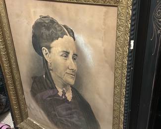 Framed Portrait with Ebonized Frame — Large framed portrait of a woman in a decorative ebonized frame with gilt inner liner and stenciled gold decoration. The portrait appears to be a charcoal or pencil studio-style drawing on paper mounted behind glass; frame shows scuffs, small chips and a split at one corner. Overall substantial piece suited for wall display in a living room or hall; framed measurement estimates provided below. Condition is fair with obvious frame wear, edge losses and age-toned paper with some foxing and minor moisture staining visible.