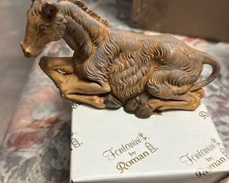 Fontanini Roman Nativity Figure — This Fontanini by Roman resin ox from a nativity set is a finely detailed reclining animal figure in warm tan coloring. Cast with realistic fur texture and molded hooves, it appears to be the original boxed piece (box shows retail sticker and wear). Measures compactly for tabletop or creche display and pairs with other Fontanini figures for a complete scene. In good collectible condition with light surface wear on the figure and shelf/age wear to the original box.