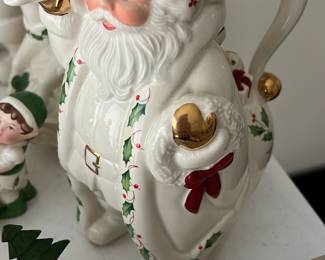 Lenox Holiday Santa Pitcher — This charming Lenox Holiday Santa Pitcher is a delightful addition to any Christmas decor collection. Crafted from fine porcelain, it features a classic white finish accented with green holly leaves, red berries, and shiny gold details on the mittens and bell. Measuring approximately 7 inches tall, this piece combines festive appeal with practical function. It is in excellent condition with no visible chips or cracks, retaining its original glossy finish. Part of the Holiday Santa Collection by Lenox, it captures the timeless spirit of the season.