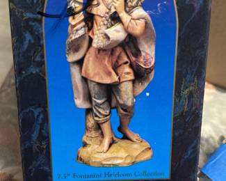 Fontanini Gabriel 7.5" Figure — This Fontanini 'Gabriel' 7.5" resin/painted figure from the Fontanini Heirloom Collection (Roman, Inc.) depicts a shepherd boy carrying a lamb and is presented with its original box. Hand-painted details show warm flesh tones, soft pastels on the clothing, and textured lamb fur for a classic Nativity/collectible look. Figure measures approximately 7.5 inches tall and is a small, shelf-ready decorative piece perfect for holiday displays or collector shelves. In good condition overall with light shelf wear to the box and minor surface wear to the paint consistent with age; no obvious chips or breaks visible in photos.