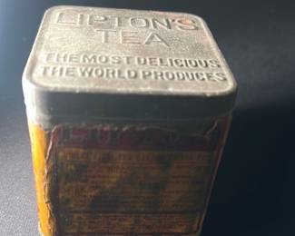 Vintage Lipton's Tea Tin — This vintage Lipton's Tea tin features embossed lettering on the lid that reads 'Lipton's Tea The Most Delicious The World Produces.' The tin is square with a distressed, aged paper label on the sides, indicative of considerable age and use. Measuring approximately 3.5 inches in height and width, this collectible tea tin is a charming piece for any tea enthusiast or vintage tin collector. The condition shows wear with some rust and label deterioration but remains structurally sound with all original parts. A nostalgic collectible from the iconic Lipton brand, ideal for display or storage.