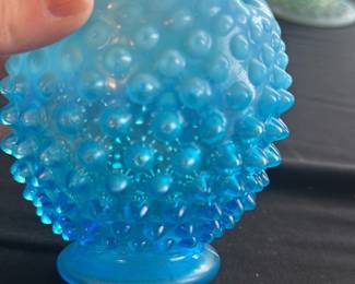 Blue Hobnail Glass Vase — This charming blue hobnail glass vase features a distinctive ruffled top edge and textured hobnail pattern throughout the body. The vase has a gradient of blue hues from a lighter shade at the top to a deeper blue at the base. Measuring approximately 4.5 inches tall and 4 inches wide, it is a lovely accent piece for any room and ideal for small floral arrangements. The vase is in good condition with minor surface wear consistent with age but no chips or cracks. Its vintage design makes it a collectible addition to glassware displays or home decor collections.