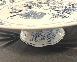 Blue Danube Pedestal Cake Plate — This elegant Blue Danube pedestal cake plate features a classic white base adorned with intricate blue floral patterns. Crafted in Japan, it showcases a delicate scalloped edge and sturdy footed base, perfect for serving cakes or desserts with style. Measuring approximately 10 inches in diameter and 4 inches tall, it adds a timeless touch to any dining setting. The plate is in excellent condition with no visible chips or cracks. A wonderful example of Blue Danube's charming design and quality craftsmanship.