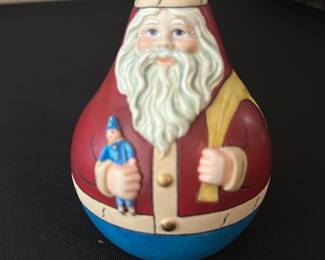 Collector's Treasury Santa Figurine — Small painted Santa figurine from 'The Collector's Treasury of Santas' series, shown in classic red coat holding a small blue toy and a yellow sack. Made of painted resin/ceramic with hand-painted details and a rounded, egg-shaped body ideal for shelf or mantle display. Measures approximately 4.5 inches tall and about 3.25 inches wide, lightweight and easy to move for seasonal decorating. Good condition with light surface wear consistent with display; base label intact identifying the series.