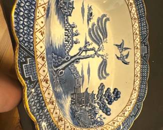 Booths Real Old Willow Blue Platter — This beautiful large platter features the classic 'Real Old Willow' pattern by Booths, made in England. The piece showcases intricate blue willow design with gold accents along the scalloped edge. Measuring approximately 11.5 inches in width, it serves as a charming decorative or serving piece in any collection. The ceramic platter is in good condition with some expected light surface wear and no visible chips or cracks. A timeless example of traditional English transferware, perfect for collectors or vintage kitchen decor.