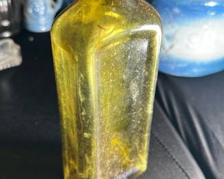 Amber Vintage Glass Bottle with Cork — This amber vintage glass bottle with a secure cork stopper offers a charming and rustic collectible piece. Featuring a rectangular form with gently rounded shoulders and a short neck, the bottle showcases classic craftsmanship with thick amber glass indicative of early to mid-20th century design. Measuring approximately 7 inches tall, 2.5 inches wide, and 2.5 inches deep, it serves as an ideal decorative item or container for liquids. The bottle is in good condition with some surface dirt and wear consistent with age but no visible cracks or chips. Its sturdy glass construction and amber color make it a desirable addition to any vintage or apothecary glass collection.