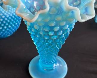 Blue Hobnail Ruffled Edge Vase — This striking blue hobnail glass vase features a distinctive ruffled edge with an opalescent finish that highlights its exquisite craftsmanship. The textured hobnail pattern adds elegance and tactile interest to this decorative piece. Measuring approximately 9 in height and 6 in across the widest ruffled opening, it serves as a beautiful accent for any master bedroom décor. The vase is in excellent condition with no chips, cracks, or damage observed. Its vintage style makes it perfect for collectors or as a statement home décor item.