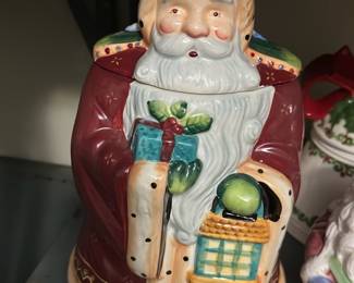 Christmas Santa Cookie Jar — Festive ceramic Santa cookie jar in classic red and cream with hand-painted green and gold accents. Features removable lid (Santa's head) and molded details showing Santa holding a gift and basket; sits flat for countertop display. Measures approximately 11 inches tall and 7 inches wide, a sturdy seasonal piece ideal for holiday kitchens or mantel displays. Good condition with minor surface wear consistent with prior use and no visible chips or cracks.