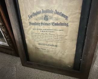 Framed Embalming Diploma — Framed diploma from the New England Institute of Anatomy for Sanitary Science & Embalming, presented in a wide wood frame with inner black rabbet and aged visible paper. The document shows heavy toning, foxing and edge wear consistent with age; frame has surface wear and small chips but remains solid for display. Overall dimensions estimated to fit a standard large diploma frame; good display piece for medical or mortuary collectors and period decor. Sold as-is due to paper age, staining, and frame blemishes; frame can be refinished and document conserved if desired.