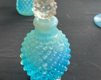Blue Hobnail Glass Perfume Bottle — This charming blue hobnail glass perfume bottle features a rounded body with raised hobnail pattern and a delicate decorative stopper. Crafted from translucent blue glass, it stands as an elegant vintage collectible, perfect for display or gentle use. The bottle measures approximately 5 inches in height including the stopper, with a 2-inch diameter base, and is light in weight, estimated at 0.5 pounds. It is in good condition with minor surface wear consistent with age, and no chips or cracks visible. This piece exemplifies mid-20th century pressed glass craftsmanship, ideal for collectors of vintage glassware.