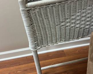 White Wicker Planter Stand — This white wicker planter stand features a woven basket design elevated on four sturdy legs. Crafted for indoor use, it provides an elegant way to display plants or organize items while adding a touch of vintage charm. Measuring approximately 23 inches tall, 18 inches wide, and 10 inches deep, it fits comfortably in small spaces such as basement rooms or sunrooms. The wicker shows minor wear and some unraveling but remains structurally sound. Ideal for adding character to home decor, this piece balances utility with classic woven craftsmanship.