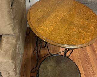 Heartback Metal Bistro Set — This charming bistro set features a metal frame with intricately twisted wirework forming heart-shaped backs on the chairs. The round wooden tabletop displays a warm natural finish, paired with cushioned seats covered in dark fabric. Measuring approximately 28 inches in height and 24 inches in table diameter, this set is perfect for small spaces or cozy corners. The sturdy iron construction and classic design remain in good condition with minor wear consistent with light use. Ideal for basement or patio use, it combines vintage romantic style with functional seating and dining space.
