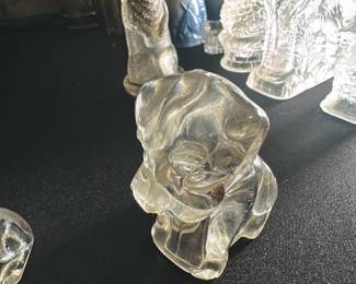 Clear Glass Puppy Figurine — This charming clear glass puppy figurine adds a whimsical touch to any collection or display. Crafted from translucent glass, it features smooth contours and detailed facial features capturing the playful essence of a puppy. Measuring approximately 3 inches tall and 2.5 inches wide, it is a delicate decorative accent perfect for shelves or desks. The figurine is in good condition with no visible chips or cracks. Ideal as a collectible or a gift item for animal lovers.