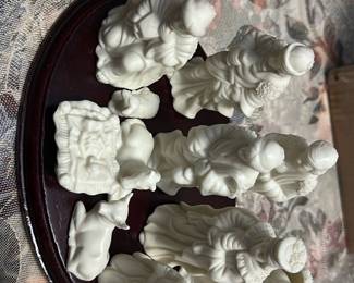White Porcelain Nativity Set — This white porcelain nativity set features a full group of sculpted figures arranged on an oval wooden base, ideal for tabletop or mantel holiday display. Each piece is molded in white porcelain with fine robes and facial details; set includes Mary, Joseph, baby Jesus in manger, three wise men, shepherd, and animals. Overall footprint of the assembled display is compact and easy to place on a shelf or table. Set is in good condition with no visible chips or cracks; base shows light surface wear consistent with normal use.