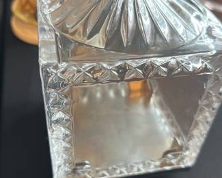 Spinning Glass Vanity Container — This spinning glass container with a weighted base is perfect for master bedroom decor or vanity use. It features a clear, cut-glass square body with detailed diamond patterning and a fluted lid topped with a glass ball finial. The base is a silver-tone metal plate that supports the spinning function, adding a unique and elegant touch. Measuring approximately 6 inches in height, 4.5 inches in width, and 4.5 inches in length, it is in good condition with some minor wear to the metal base. This decorative piece combines both style and function for elegant room accents.