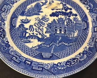 Wedgwood Blue Willow China Plate — This classic Wedgwood Blue Willow china plate features a traditional blue and white pattern depicting a Chinese-inspired landscape. Made in England, this fine china plate is crafted from high-quality porcelain with intricate border designs and central scenic motifs. The plate measures approximately 10.25 inches in diameter, making it an ideal decorative or dining piece. It is in good condition with typical age-related crazing and minor surface wear visible on close inspection. Wedgwood's timeless design and craftsmanship make this plate a valued collectible for both everyday use and display.