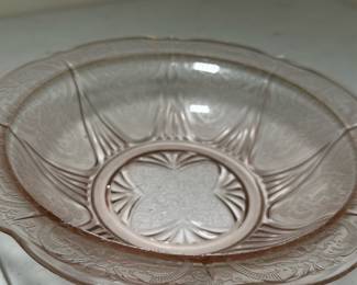 Pink Depression Glass Bowl — This delicate pink Depression glass bowl features classic pressed floral and geometric patterns that are emblematic of 1930s American glassware. Crafted from translucent pink glass, it has an elegant scalloped edge and a shallow, rounded form ideal for serving or decorative display. Measuring approximately 8 inches in diameter and 2.5 inches in height, this bowl is a charming example of vintage Depression glass collectibles. It is in good condition with some minor surface wear and a small chip on the rim consistent with vintage use. Perfect for collectors or as a vintage accent piece in any home décor.