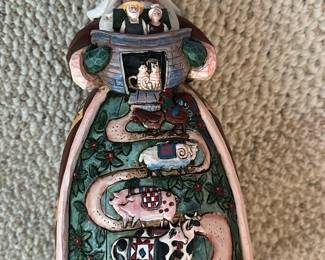 Jim Shore Noah's Ark Santa Figurine — Whimsical Jim Shore Santa with Noah's Ark motif, featuring hand-painted folk-art details and carved-look textures. Made of polystone with multiple animal motifs winding up the front of the robe and a tiny ark held in Santa's hands. Measures approximately 9.5 inches tall and is a compact holiday display piece for a mantel or shelf. In good condition with minor surface wear to paint consistent with gentle use and display.