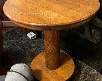 Round Oak Side Table — This solid oak round side table features a sturdy central pedestal and a circular base, offering a classic and durable design. Its warm oak finish brings a cozy, traditional look perfect for a living room setting. The table measures approximately 24 inches in height and 20 inches in diameter, making it a versatile accent piece. It is in good condition with some minor surface wear consistent with gentle use. This table exemplifies straightforward craftsmanship suitable for various interior styles.