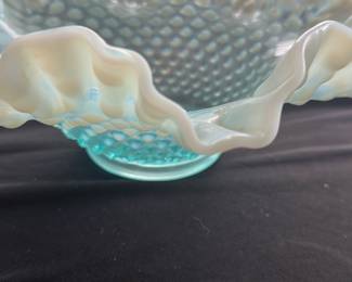 Fenton Aqua Opalescent Hobnail Bowl — This Fenton aqua opalescent hobnail bowl features the signature ruffled edge and raised hobnail pattern typical of classic Fenton art glass. Crafted from opalescent carnival glass, this bowl exhibits a beautiful light blue color that fades to milky white along the edges, adding visual depth and charm. Measuring approximately 4.5 inches tall with a 10-inch width and 10-inch length, it serves both as an elegant decorative piece and a functional bowl. The bowl is in excellent condition with no chips or cracks. A fine example of mid-20th century American glass artistry, this piece is a collectible treasure for Fenton glassware enthusiasts.