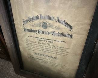 Framed Embalming Diploma — Framed diploma from the New England Institute of Anatomy for Sanitary Science & Embalming, presented in a wide wood frame with inner black rabbet and aged visible paper. The document shows heavy toning, foxing and edge wear consistent with age; frame has surface wear and small chips but remains solid for display. Overall dimensions estimated to fit a standard large diploma frame; good display piece for medical or mortuary collectors and period decor. Sold as-is due to paper age, staining, and frame blemishes; frame can be refinished and document conserved if desired.