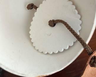 Hand-Painted Ceramic Hanging Bell — This charming hand-painted ceramic hanging bell features a natural scene with dandelion-like floral motifs accented by a light blue and sandy brown glaze. Finished with a sturdy brown cord for hanging, the bell's underside includes a decorative scalloped ceramic clapper. Measuring approximately 5 inches in height and 4 inches in diameter, it makes a delightful decor accent for both indoor and outdoor spaces. The bell is in good condition with minor wear consistent with age and gentle use. Its artisanal style adds a rustic and natural element to any bonus up room or garden setting.