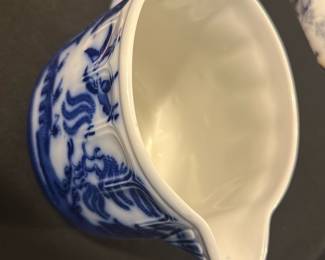 Doulton Blue White Pitcher England — This charming Doulton pitcher from England features a classic blue and white design, characteristic of traditional Doulton ceramics. The pitcher displays intricate blue patterns on a white background, including detailed foliage and landscape motifs. It measures approximately 5 inches tall and 5.5 inches wide, making it a practical and decorative piece for kitchen or dining use. In very good condition, the pitcher shows no visible chips or cracks, with a well-preserved glaze. Marked on the bottom with the Doulton maker's mark and 'Made in England', this piece reflects authentic English craftsmanship.
