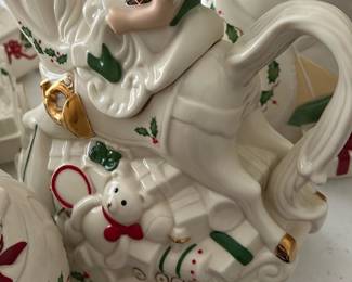 Lenox Elf Rocking Horse Teapot — This charming Lenox Holiday Elf and Rocking Horse Teapot is a festive addition to any Christmas decor. Crafted from fine porcelain, it features a detailed elf figure riding a white rocking horse adorned with holly, gold accents, and a teddy bear motif. The teapot measures approximately 7 inches tall, 9 inches wide, and 5 inches deep, making it a delightful centerpiece for holiday gatherings. It is in excellent condition with no chips, cracks, or visible wear, and includes its original packaging. A collectible piece from Lenox's For The Holidays series, perfect for adding whimsical charm to your seasonal table.