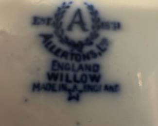 Allertons Ltd Blue Willow Sugar Bowl — This charming sugar bowl features the classic Allertons Ltd English Blue Willow pattern with its iconic blue and white design. Crafted from fine porcelain, it includes a fitted lid and dual handles for ease of use. Measuring approximately 3.5 inches in height and 5 inches wide including handles, it is a perfect addition to any tea or dining set. The piece is in good condition with mild wear consistent with age and no visible chips or cracks. Marked on the bottom with the Allertons Ltd maker's stamp and 'Made in England' designation, this bowl represents fine English china craftsmanship.