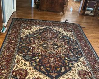 Mahdavi's A&A Wool Area Rug 79x96 — This Mahdavi's A&A Rug Co. area rug is a genuine handmade wool piece from India, featuring a classic ornate pattern in rich blues, reds, and cream tones. The rug measures 79 by 96 inches, crafted from 100% wool with a hand-tufted pile that has been specially hand washed. It showcases an intricate design with a central medallion and floral motifs surrounded by detailed borders, suitable for enhancing any living room space. The rug is in good condition with a gentle used appearance and no major visible damage. Recommended for anyone seeking a quality handmade wool rug with timeless style from an established maker.
