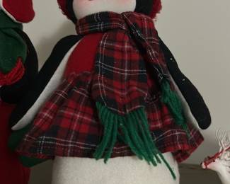 Red Plaid Penguin Holiday Figure — Charming plush penguin holiday figure dressed in red plaid with a matching hat and green fringe scarf. Made of soft felt and fabric with stitched facial features and a weighted plush base to stand upright on shelves or mantels. Measures approximately 14 inches tall with a sturdy base making it an easy seasonal display piece. Good used condition with light surface dust and a small fabric pull on the base noted in photos.