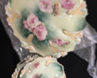 6 pc RS Prussia Handpainted Bowl Set — This beautiful RS Prussia bowl set features handpainted pink roses on a soft green and cream background with ornate scalloped edges. The set includes a large bowl and several smaller matching bowls, each showing delicate floral detail and gold trim. The large bowl measures approximately 12 in in diameter and the smaller bowls about 7 in. These pieces are in good condition with minor wear consistent with their age, showcasing elegant late 19th to early 20th-century porcelain craftsmanship. A charming addition to any vintage ceramic or china collection.