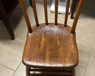 Lion Head Side Chair — Simple wooden Windsor-style side chair with curved hoop back and five spindles, crafted in a warm medium-brown finish. Solid wood seat with turned legs and stretchers shows surface wear, scuffs and finish loss consistent with everyday use. Overall sturdy and functional for seating in a master bedroom or dining nook; compact footprint makes it easy to move. Condition is fair with visible wear on seat underside and minor finish dings but no major structural damage.