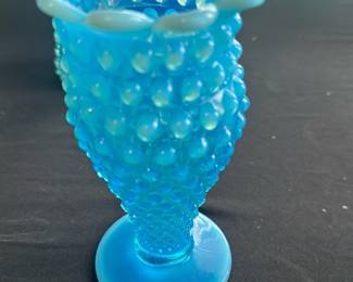 Blue Hobnail Glass Vase — This charming blue hobnail glass vase features a distinctive ruffled top edge and textured hobnail pattern throughout the body. The vase has a gradient of blue hues from a lighter shade at the top to a deeper blue at the base. Measuring approximately 4.5 inches tall and 4 inches wide, it is a lovely accent piece for any room and ideal for small floral arrangements. The vase is in good condition with minor surface wear consistent with age but no chips or cracks. Its vintage design makes it a collectible addition to glassware displays or home decor collections.