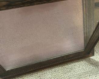 Antique shadow box frame — Attractive wood-grain decorative picture frame with textured carved edging and a dusty rose backing board. The frame appears to be constructed from molded wood or oak-look composite with a glass front and hanging chain on the back. Overall size is moderate and suitable for tabletop or wall display; lightweight and easy to hang. Frame shows light wear to finish and a small tear in the backing paper but glass and molding are intact.