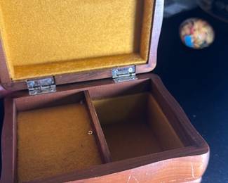 Wood Jewelry Box with Felt Lining — This charming wood jewelry box features a gently curved rectangular form with a warm brown finish and a soft yellow felt interior lining. It includes a divided compartment inside for organizing small items. The box measures approximately 4.5 inches wide, 3.5 inches deep, and 3 inches high, resting on four small rounded feet. Some surface wear and minor scratches are visible, consistent with age and use, but the box remains sturdy and functional. A classic piece ideal for personal keepsakes, storing jewelry or small collectibles.