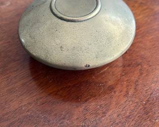 Vintage Small Metal Trinket Box — This vintage small metal trinket box features a simple, round design with a removable lid. The box has a smooth matte finish with subtle patina indicative of age, adding character to the piece. Measuring approximately 2.5 inches in diameter and 1 inch in height, it is perfect for storing small items or keepsakes. The condition shows natural wear consistent with vintage use, with no visible dents or damage. Its compact size and classic design make it a charming addition to any collection or desk.