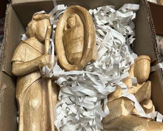 mesa wood nativity figures — Hand-carved Mesa Wood nativity figures including Mary, baby Jesus in manger, and a standing shepherd/figure. The set is carved from light-colored wood with a simple, folk-art style and comes stored in its original cardboard box labeled "MESA WOOD." Figures are small and boxed for easy display or gift use. Overall good condition with light surface handling wear and no major chips or breaks noted. Great for holiday tabletop displays or collectors of handcrafted folk nativity sets.
