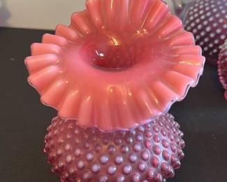 Hobnail Fenton Glass Vase — This charming pink Hobnail vase by Fenton Glass features a ruffled top and distinctive hobnail texture on the body, creating an elegant vintage decorative piece. Crafted from high-quality opalescent glass, it showcases a rich pink color that enhances its classic appeal. Measuring approximately 6 inches in height and 4.5 inches in width, this vase is perfect as an accent piece for any room. It is in excellent condition with no chips or cracks visible. A lovely collectible piece representing mid-20th century American glass artistry.