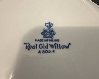 Blue Willow real old willow  Plate — This charming Soothe 'Real Old Willow' scalloped plate from England showcases classic blue and white Willow pattern imagery with gold trim. Crafted from fine ceramic, it features a detailed bridge, willow tree, and pagoda scene in blue hues against a white base accented by an intricate border design. The plate measures approximately 9.5 inches in diameter, making it suitable for display or dining use. It is in good condition with minor surface discoloration noted but no chips or cracks visible. A lovely example of traditional English transferware from a respected maker.