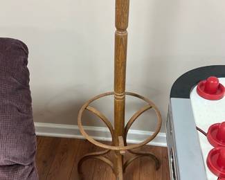 Wooden Bentwood Coat Rack — This classic wooden bentwood coat rack offers both style and function with its curved arms and sturdy support. Crafted from solid wood with a natural finish, it features multiple hooks at the top and a circular base designed for stability. Standing approximately 68 inches tall, it fits perfectly in a basement room or entryway for hanging coats, hats, and scarves. The coat rack is in good condition with minor signs of wear consistent with age and use. Its timeless design makes it a versatile piece for various decor styles.