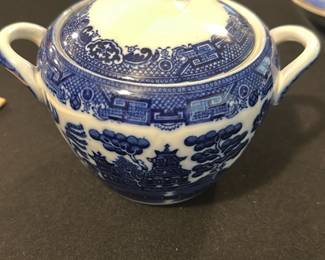 Allertons Ltd Blue Willow Sugar Bowl — This charming sugar bowl features the classic Allertons Ltd English Blue Willow pattern with its iconic blue and white design. Crafted from fine porcelain, it includes a fitted lid and dual handles for ease of use. Measuring approximately 3.5 inches in height and 5 inches wide including handles, it is a perfect addition to any tea or dining set. The piece is in good condition with mild wear consistent with age and no visible chips or cracks. Marked on the bottom with the Allertons Ltd maker's stamp and 'Made in England' designation, this bowl represents fine English china craftsmanship.